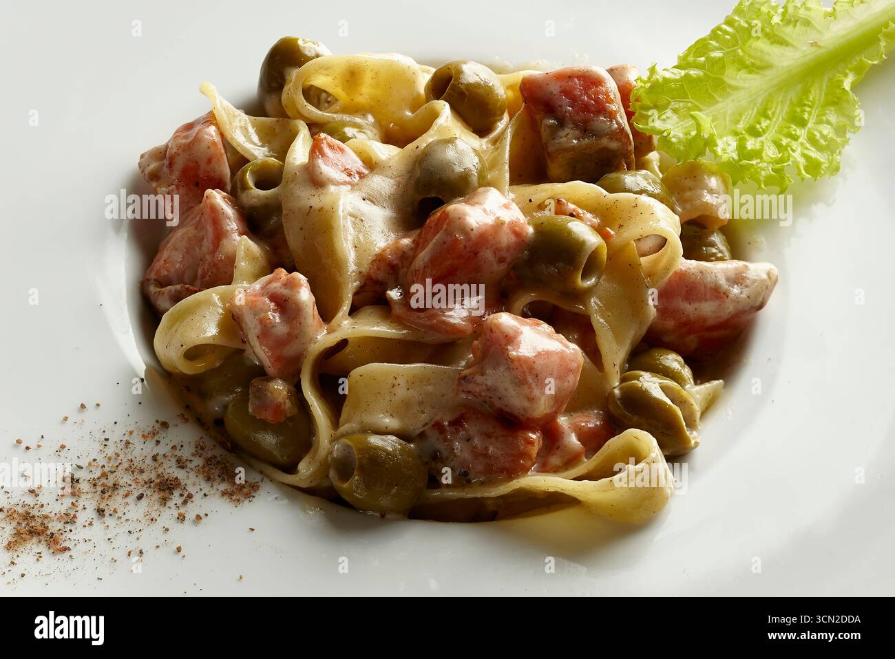 Primo piano di cremoso prosciutto e pasta ai funghi guarniti con foglie di lattuga, studiate per la fotografia del cibo e immagini di scorta con spazio per le copie. Foto Stock
