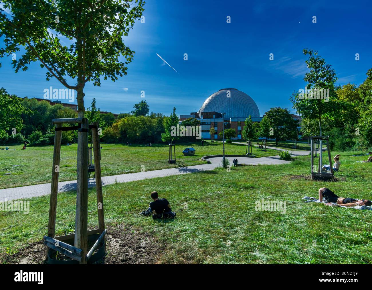 Atmosfera estiva rilassata nel Parco Ernst Thälmann con persone sul prato e la cupola del planetario Zeiss sullo sfondo. Foto Stock