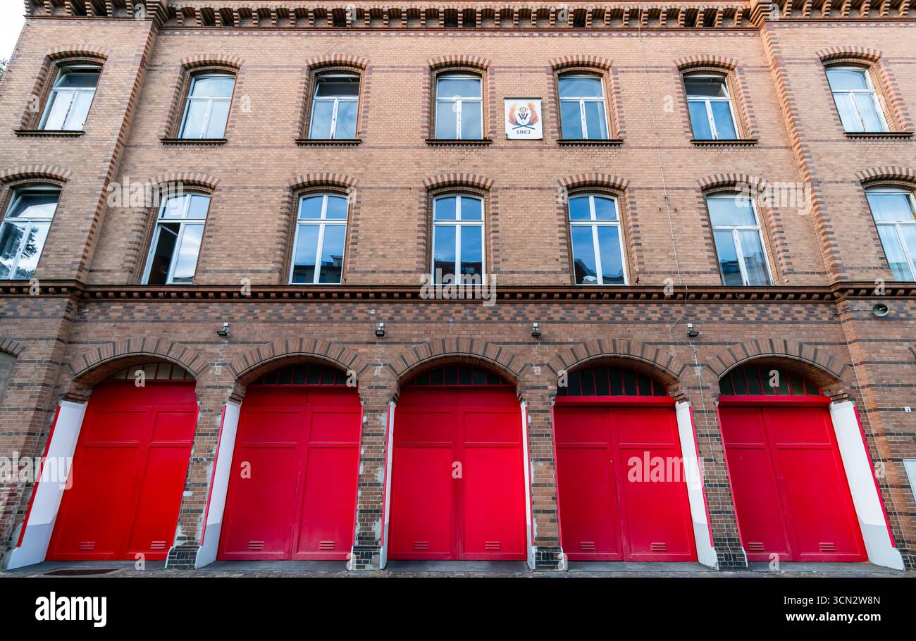 Vista frontale della caserma dei pompieri del XIX secolo (Feuerwache) a Prenzlauer Berg con iconiche porte rosse e facciata in mattoni neomanici. Foto Stock