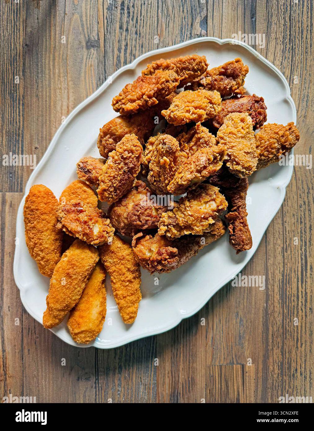 piatto di ali di pollo fritte e pezzi di filetto su un tavolo di legno, vista dall'alto Foto Stock