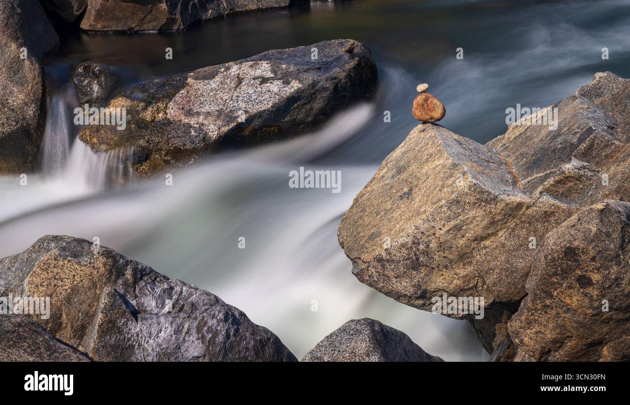 Due ciottoli bilanciati sulla roccia nella cascata illustrano resilienza, forza, equilibrio, calma, quiete e tranquillità. Icicle Creek Washington Foto Stock