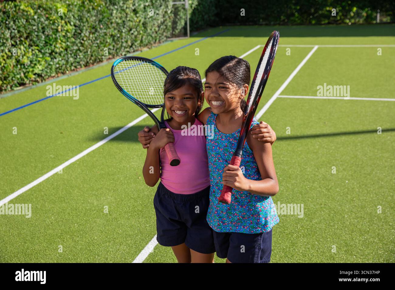 Ragazze asiatiche amiche che condividono momenti gioiosi tenendo racchette sul campo all'aperto con linee Foto Stock