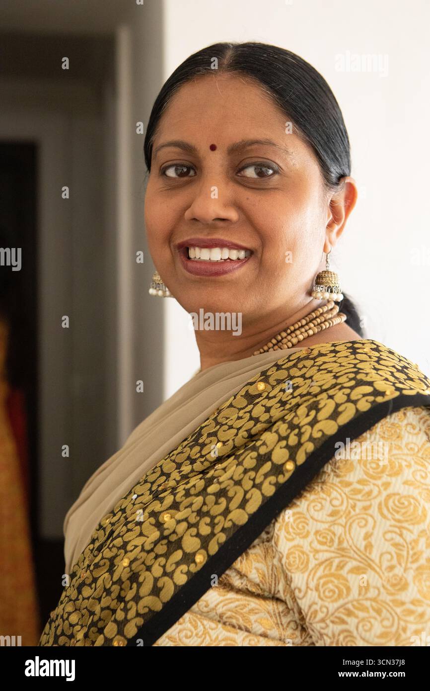 Donna indiana in piedi nel corridoio con orecchini sari jhumka collane con perline, bindi rossi Foto Stock