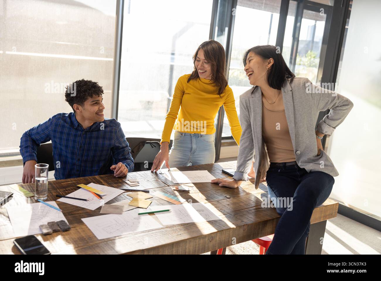 Diversi colleghi che indossano abiti casual e collaborano a disegnare schizzi al tavolo dell'ufficio Foto Stock