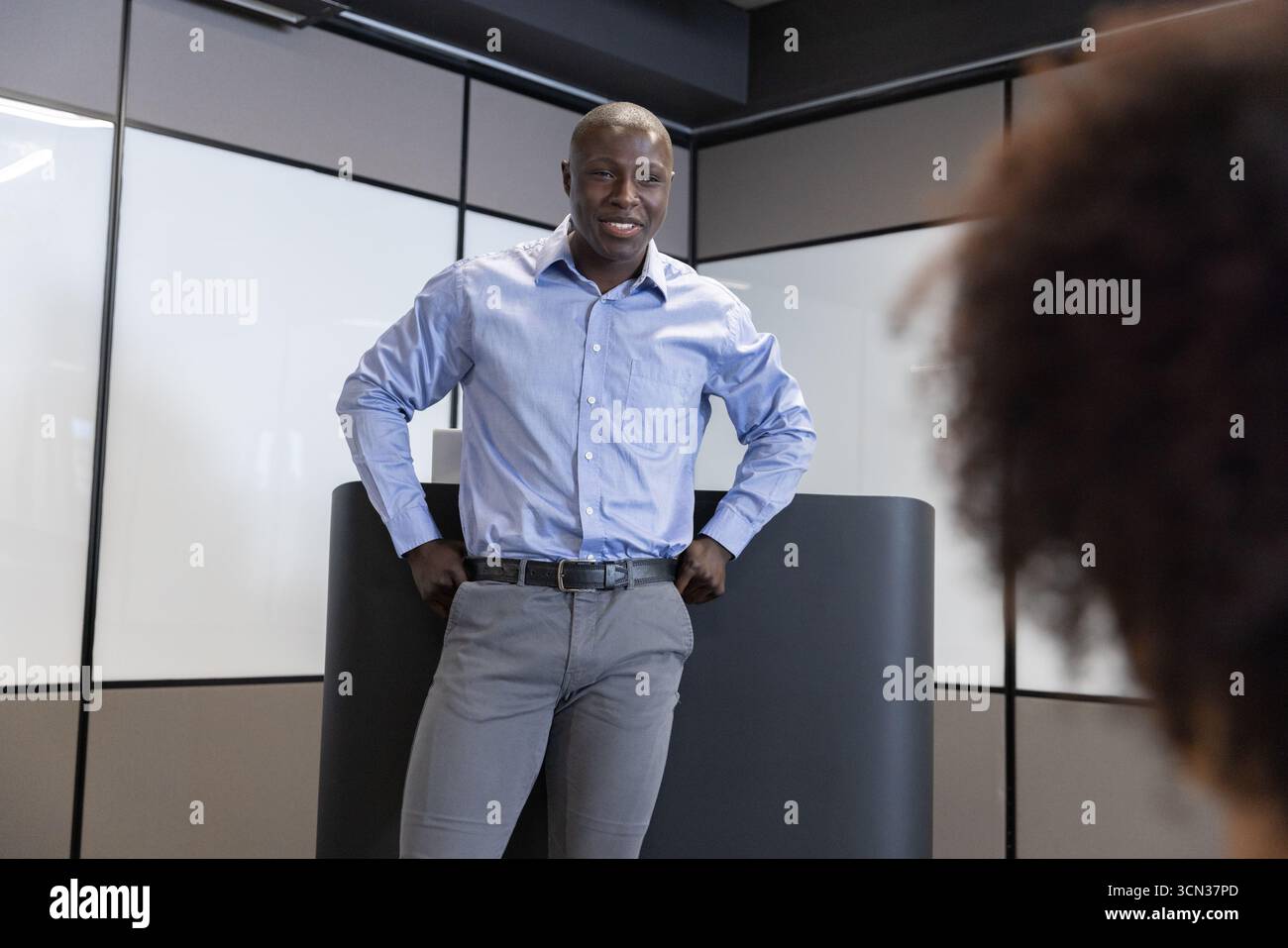 Colleghi diversi che si trovano sul podio e parlano con i colleghi in ufficio con pannelli di vetro Foto Stock