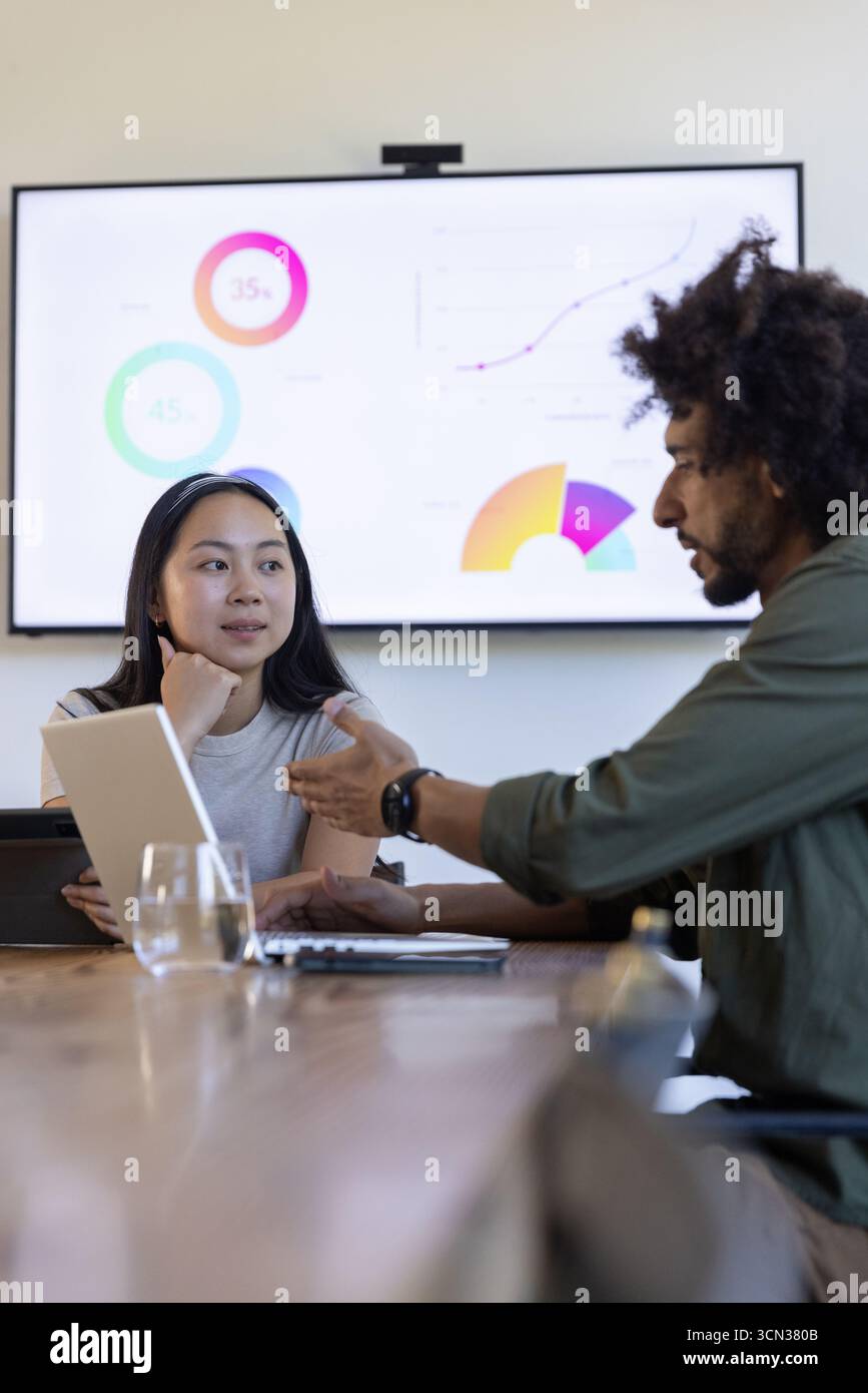 Colleghi diversi che esaminano le carte visualizzate mentre tengono in mano un tablet digitale nella sala conferenze Foto Stock