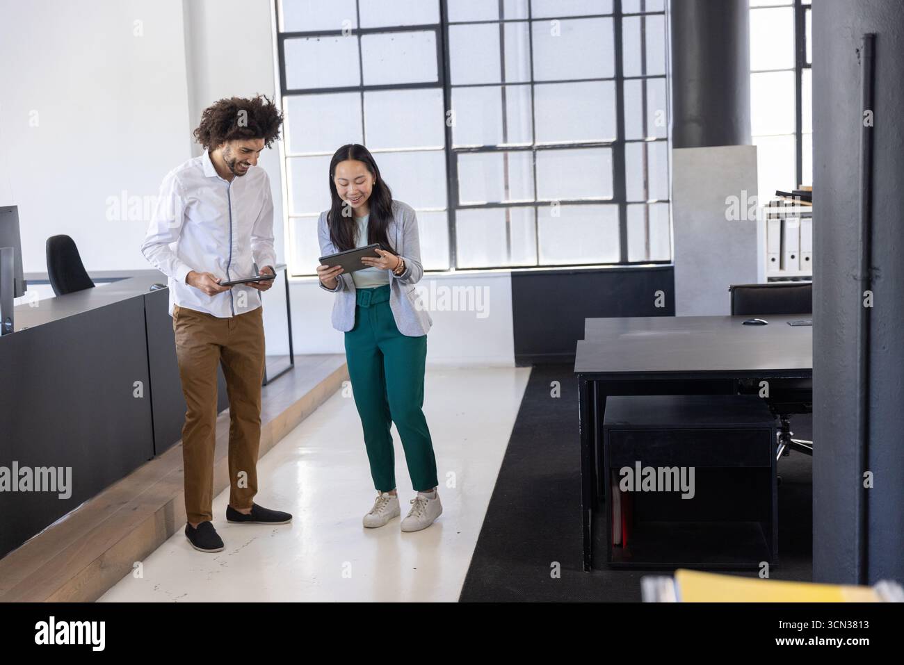 Colleghi diversi che discutono di report sui tablet in un moderno ufficio open space Foto Stock