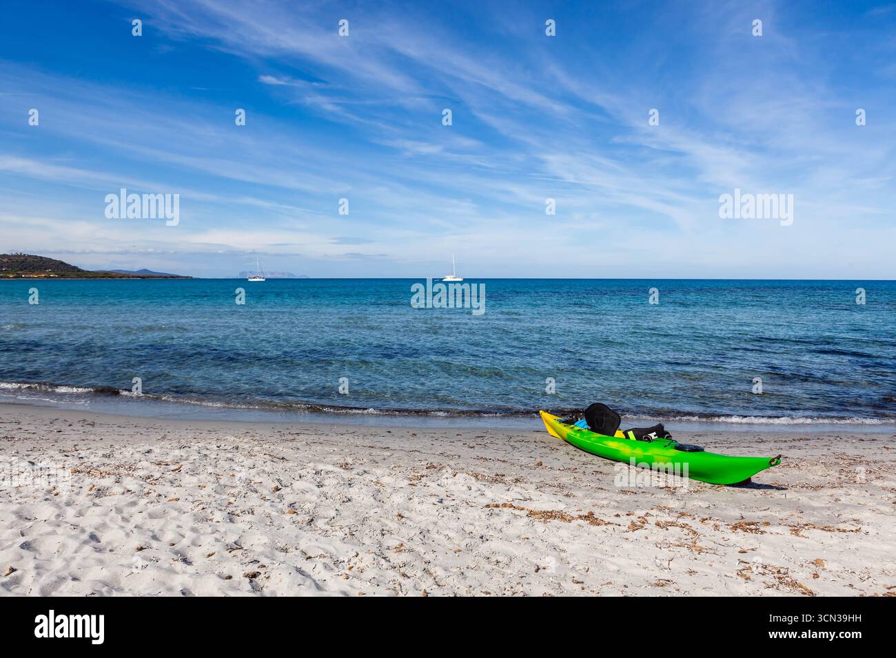 Kayak verde sulla spiaggia sabbiosa della Sardegna. Mare Mediterraneo turchese color smeraldo e yacht bianchi ancorati sullo sfondo. Italia. Foto Stock