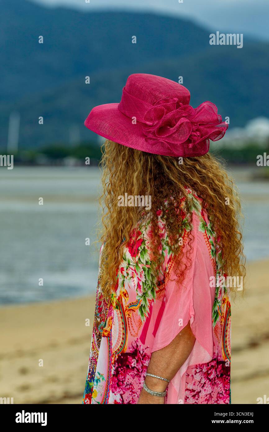 retro di una signora in piedi barche che guardano spiaggia colorano l'abito completo lunghi capelli marroni ricci 50 più modelli modelli maturi che modellano l'australia australiana Foto Stock