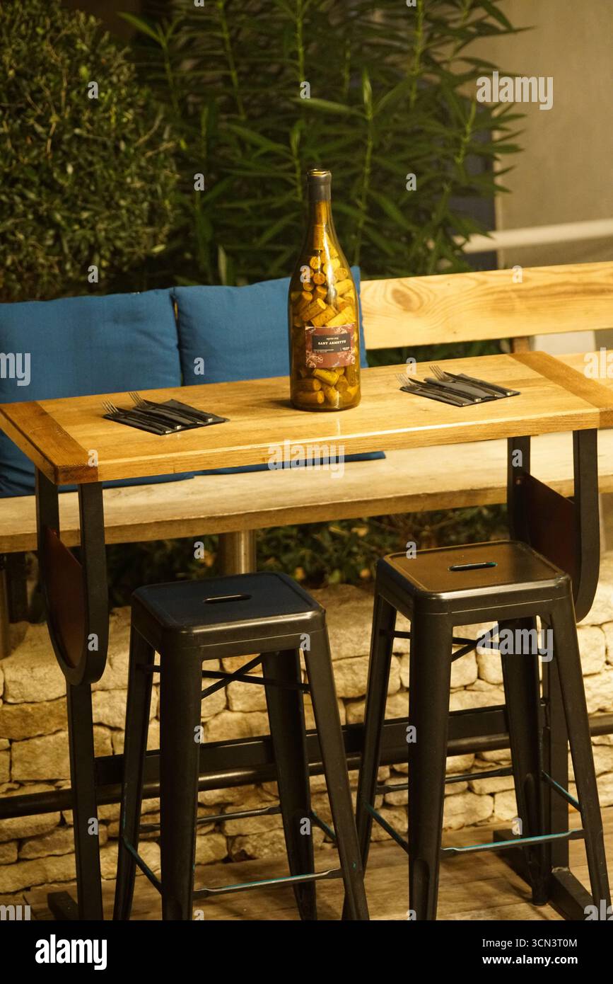 Tavolo all'aperto con bottiglia di vino e mandorle per cene informali sul patio. Bonifacio, Corsica, Francia Foto Stock