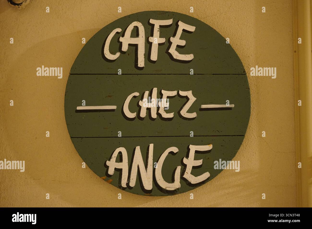 L'insegna rotonda del caffè francese d'epoca "Cafe Chez Ange" sulla calda parete per la Rustic Street Vibe. Bonifacio, Corsica, Francia Foto Stock