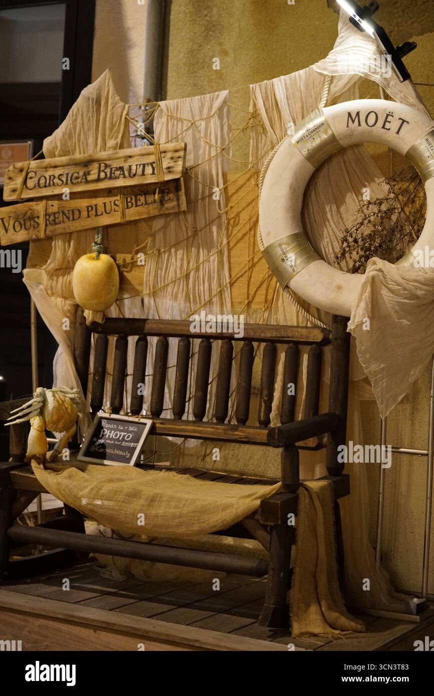 Decorazioni rustiche sul mare con bagnoia Moët, cartelli Corsica e banchi d'epoca. Bonifacio, Corsica, Francia Foto Stock