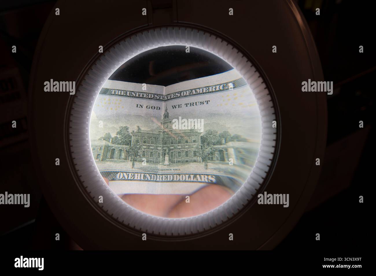 Il retro di una banconota americana da cento dollari che viene guardata attraverso una lente d'ingrandimento. Primo piano. Foto Stock