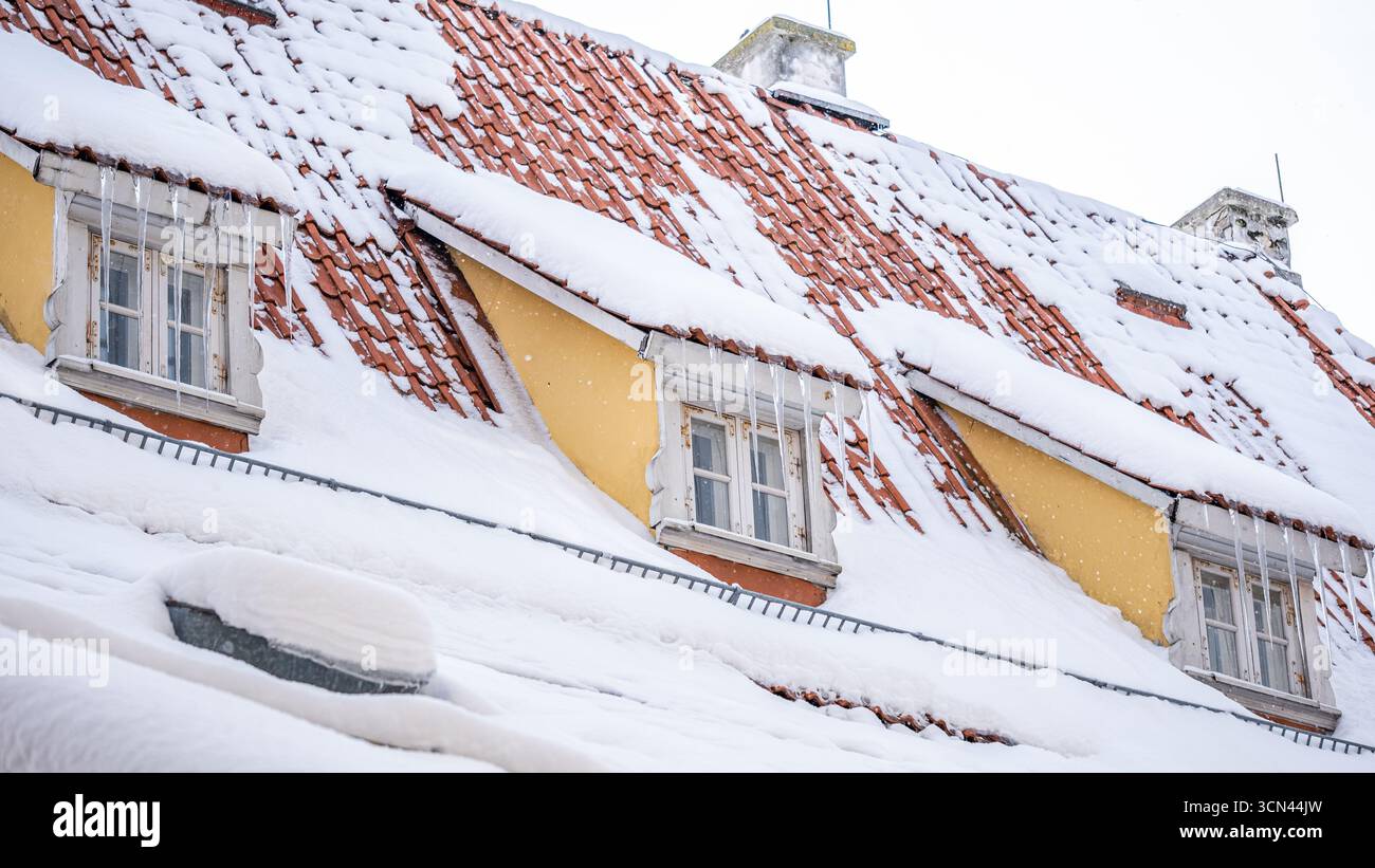 Le tegole di terracotta ricoperte di neve mettono in risalto i metodi di costruzione tradizionali, offrendo proprietà di durata, migliorando l'estetica invernale e. Foto Stock