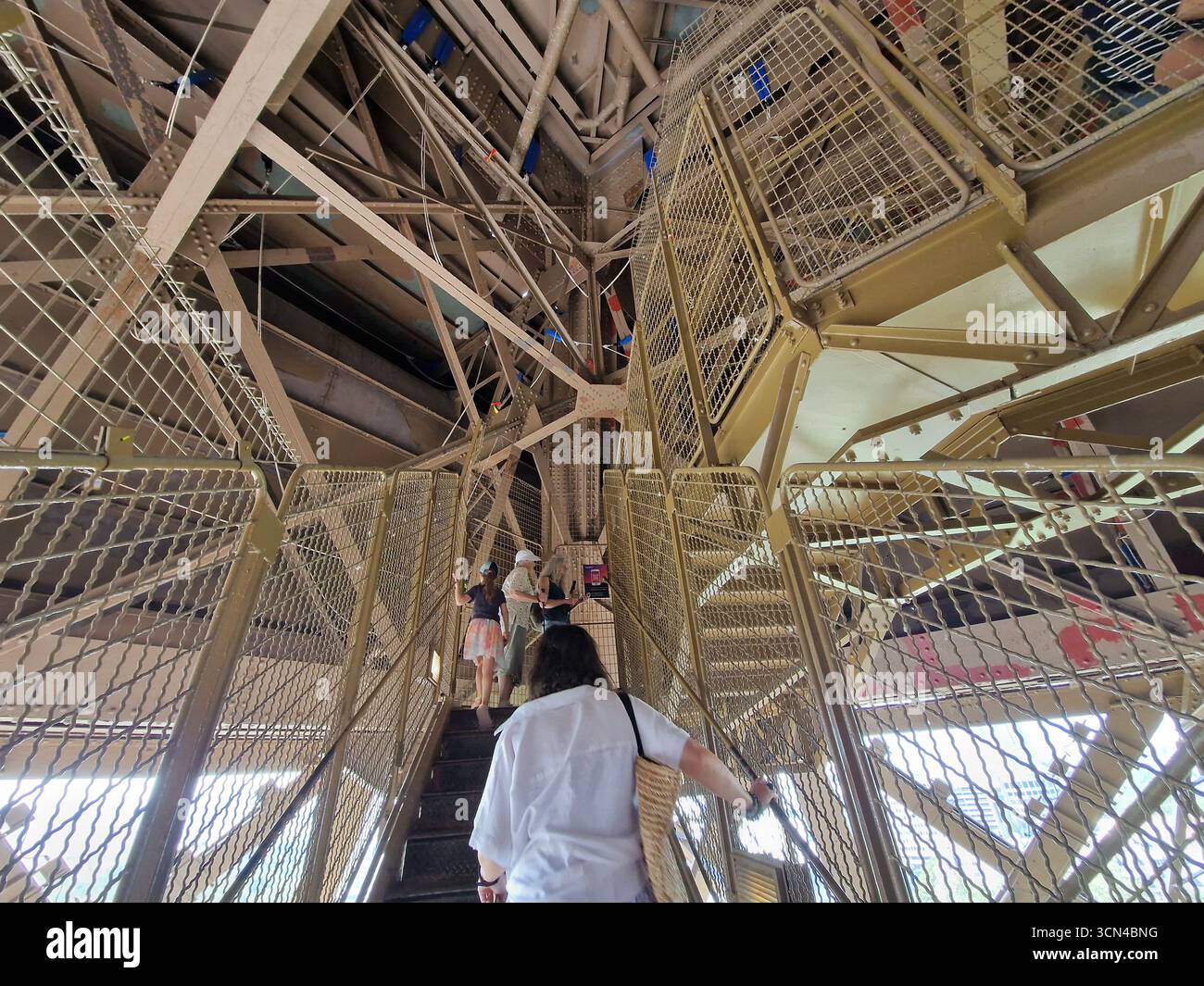Parigi, Francia - 8 giugno 2023: I turisti camminano su e giù per le scale della Torre Eiffel in una giornata di sole. Foto Stock