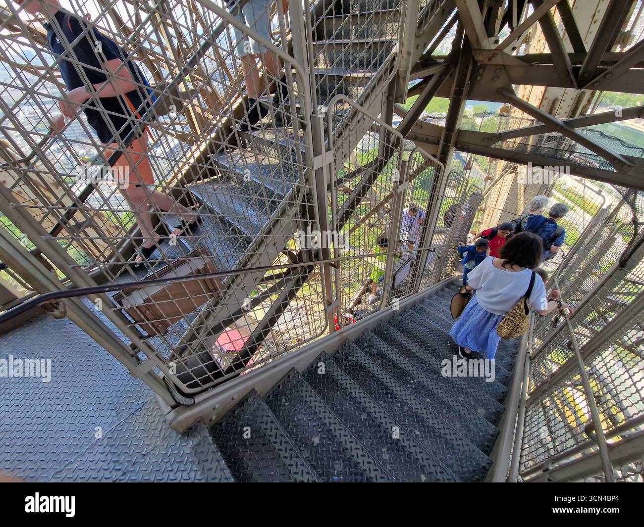 Parigi, Francia - 8 giugno 2023: I turisti camminano su e giù per le scale della Torre Eiffel in una giornata di sole. Foto Stock