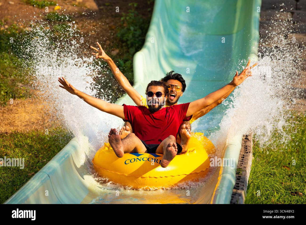 Due amici che si divertono con uno scivolo acquatico - divertimento all'aperto Foto Stock