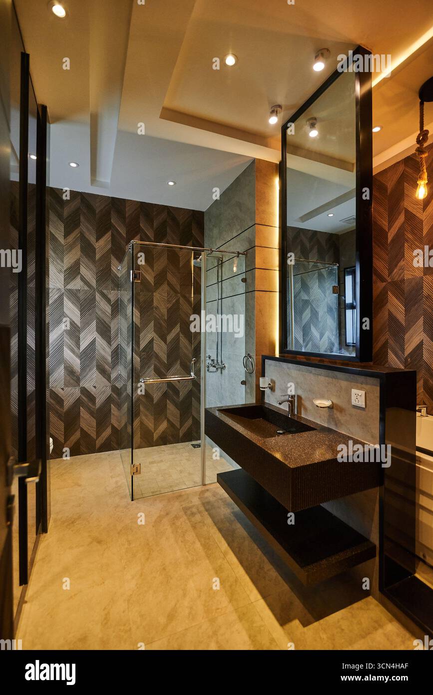 Bagno moderno con finiture in legno scuro, doccia in vetro e finiture eleganti. Il design crea uno spazio lussuoso e pulito per rilassarsi e Foto Stock