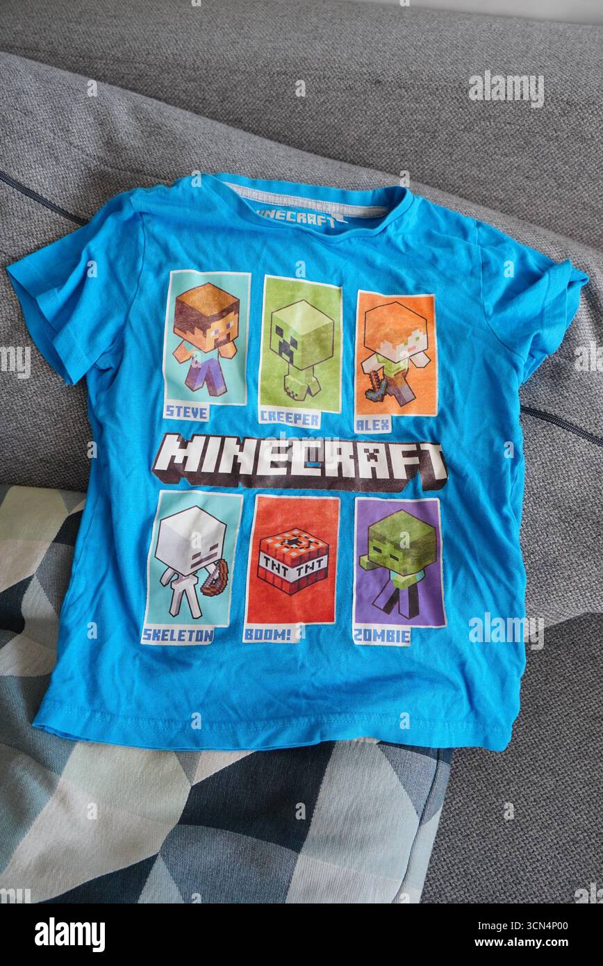 Una maglietta blu Minecraft con illustrazioni colorate dei personaggi, adatta a bambini che amano giocare e divertirsi. Foto Stock