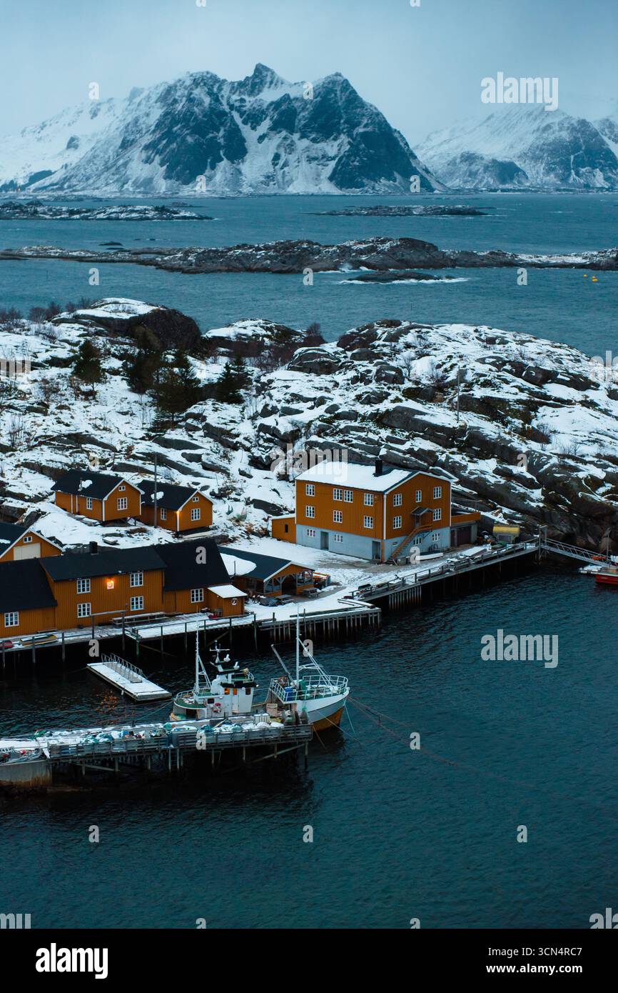 Villaggio costiero innevato con casette e barche arancioni Foto Stock
