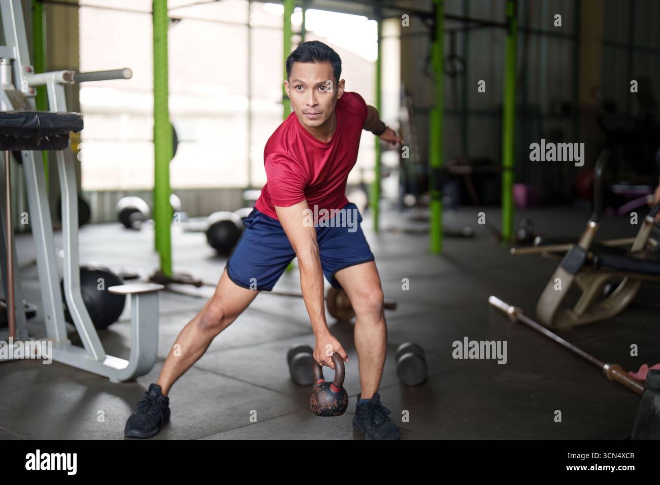 Allenamento di forza. Giovane che esegue esercizi di kettlebell in palestra. Foto Stock