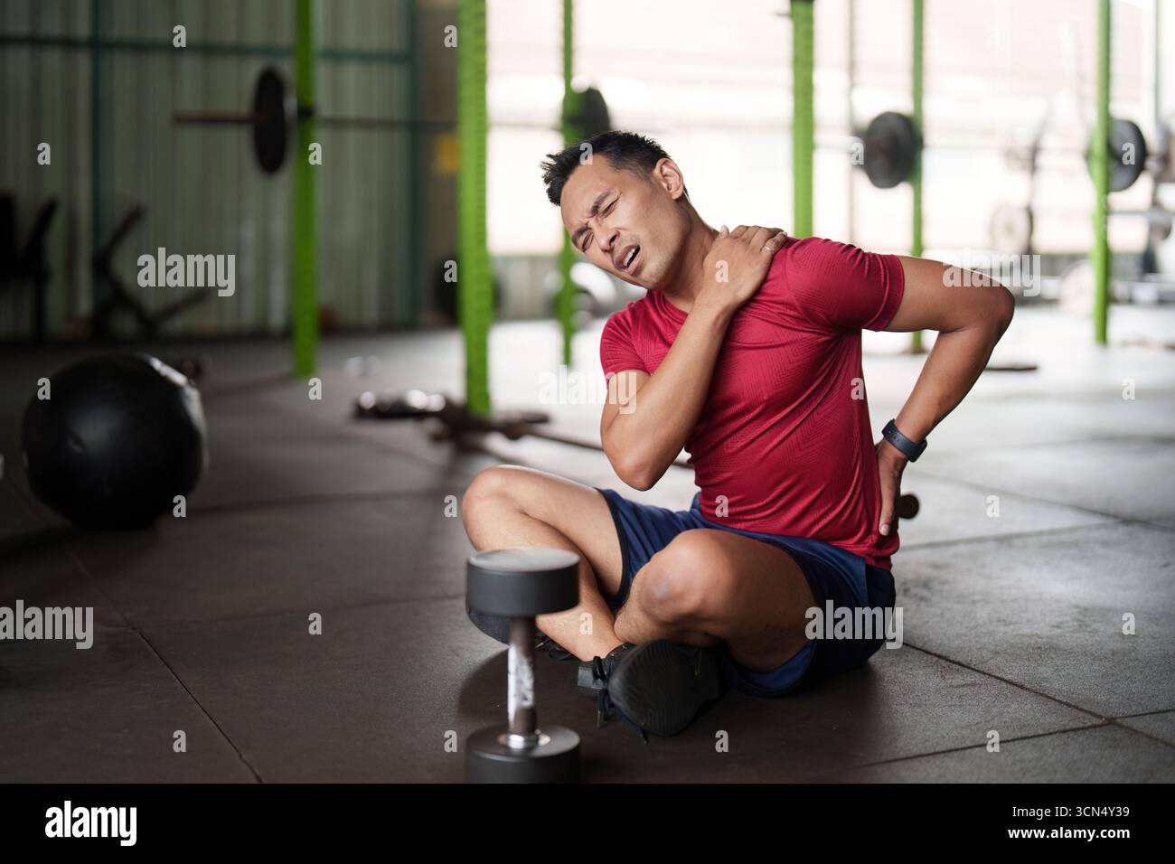 Infortunio al fitness. Giovane che soffre di dolore alle spalle durante l'allenamento in palestra. Foto Stock