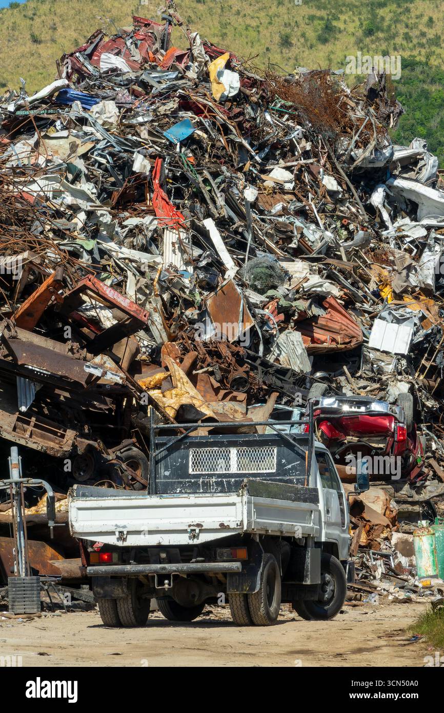 Camion davanti a un grande cumulo di rottami metallici in un discarica per il riciclaggio Foto Stock