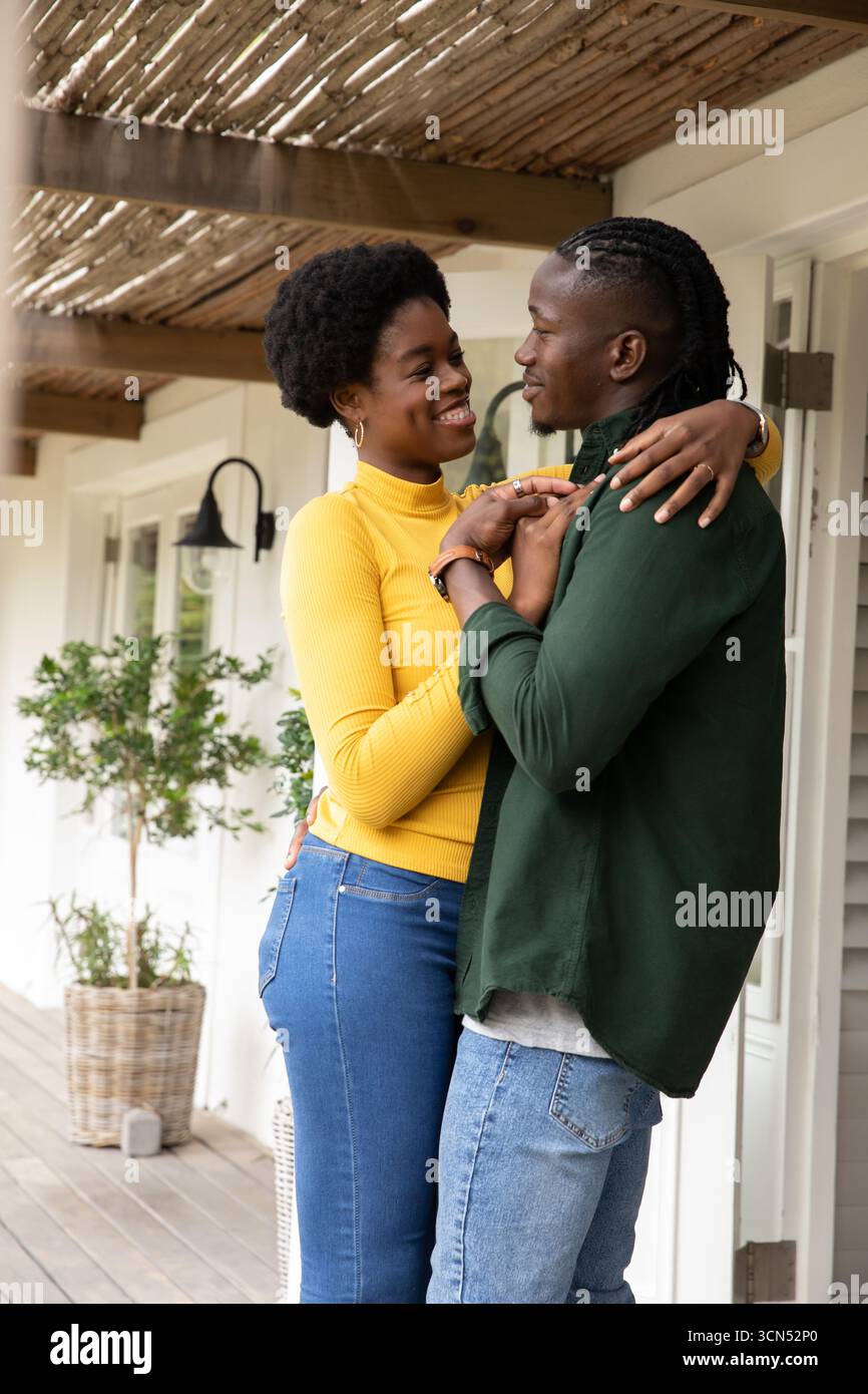 Coppia afroamericana che abbraccia, sorride sul portico sotto il pergolato con lanterna, copia spazio Foto Stock