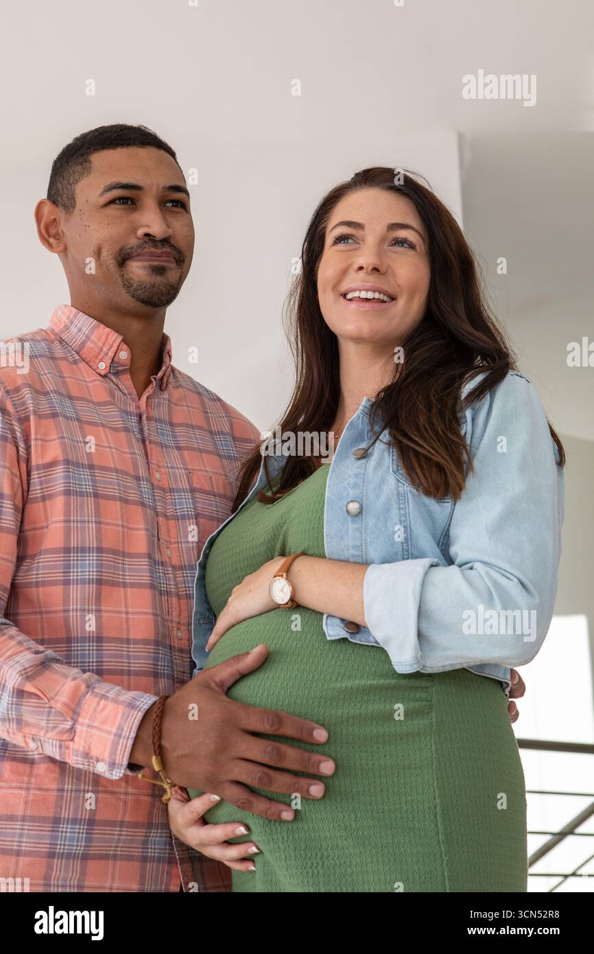 Diverse coppie che si aspettano di mettere le mani su un batuffolo e stare in piedi all'interno di casa vicino alla ringhiera delle scale Foto Stock