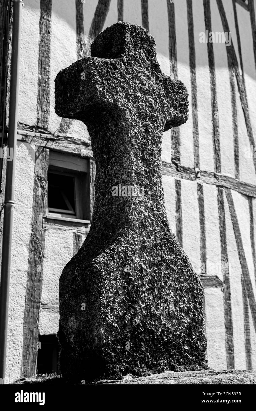 Un'antica croce cattolica in pietra si erge solennemente nella campagna francese, infranta da secoli di fede, storia e tempo. Foto Stock