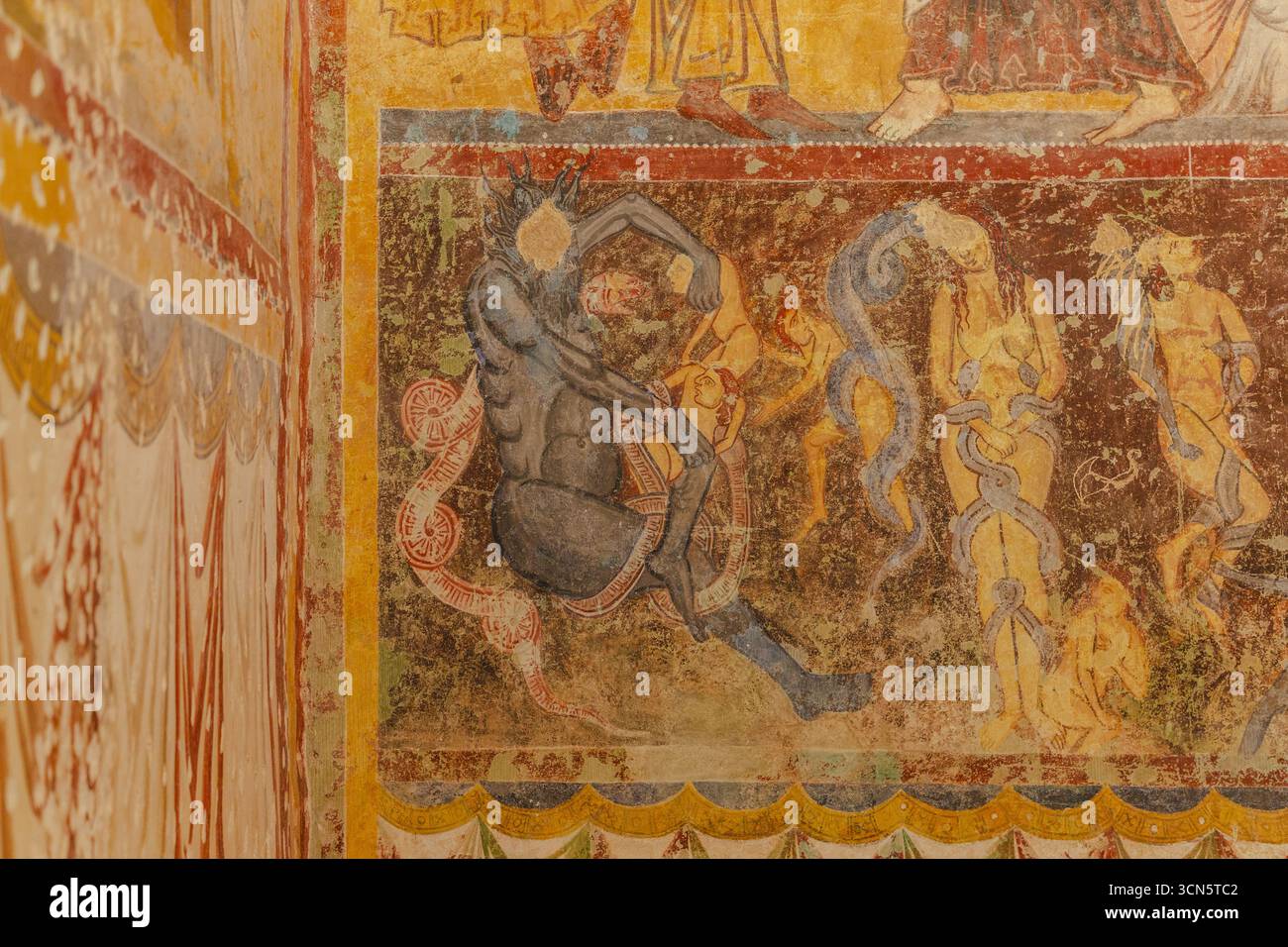 Veduta delle antiche mura adornate da vivaci e sbiaditi affreschi raffiguranti figure e motivi, una storia visiva incisa nel tempo, Bominaco, Abruzzo, Italia. Foto Stock