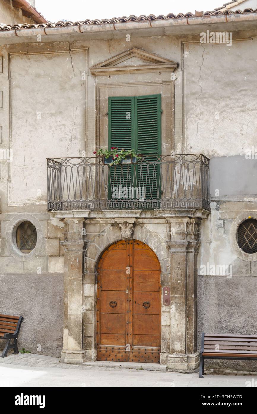 Vista di un vecchio edificio con una porta arancione brillante e sorprendenti persiane verdi da una prospettiva di terra, Scanno, Abruzzo, Italia. Foto Stock