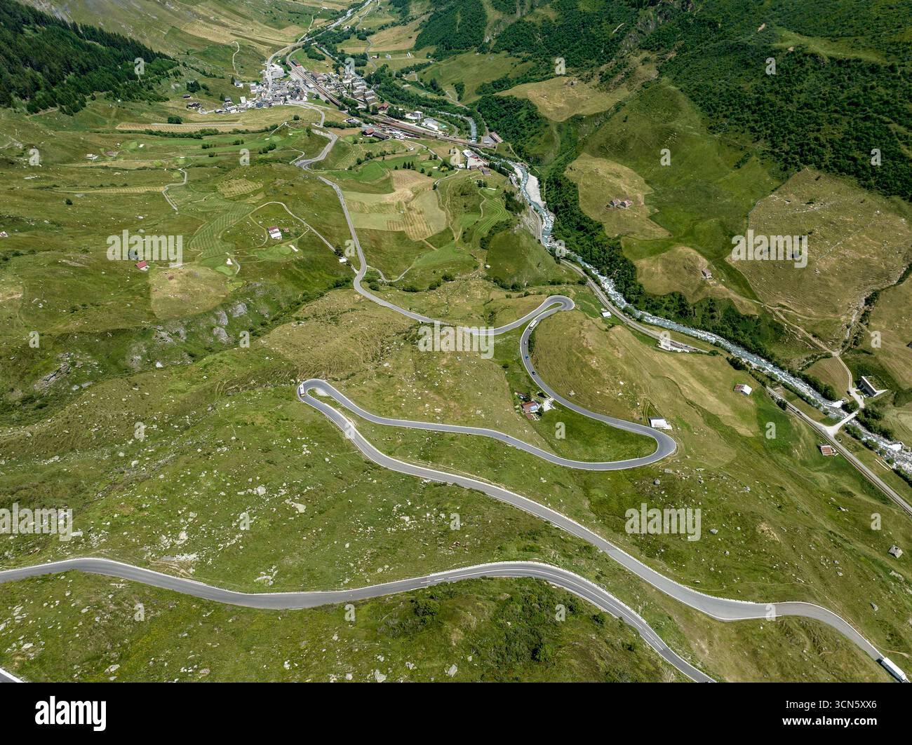 Veduta aerea di strade tortuose che serpeggiano nel verde del paesaggio, collegando il paese annidato nella valle, passo del San Gottardo, Ticino, Svizzera. Foto Stock
