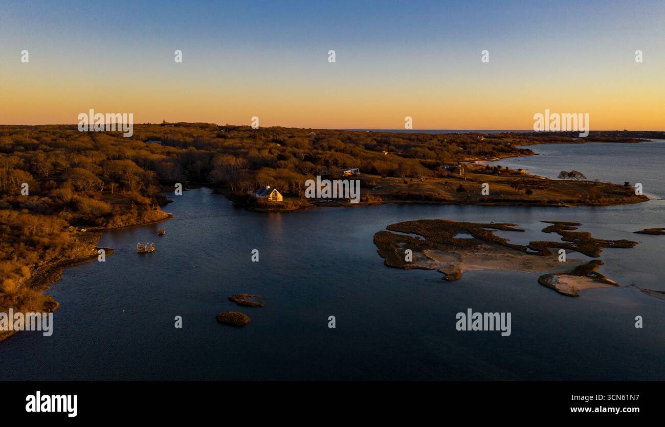 Vista aerea della luce dorata del sole che baciano le acque tranquille che circondano Chappaquiddick Island, gettando lunghe ombre attraverso il paesaggio paludoso, Martha's Vineyard, Massachusetts, Stati Uniti. Foto Stock