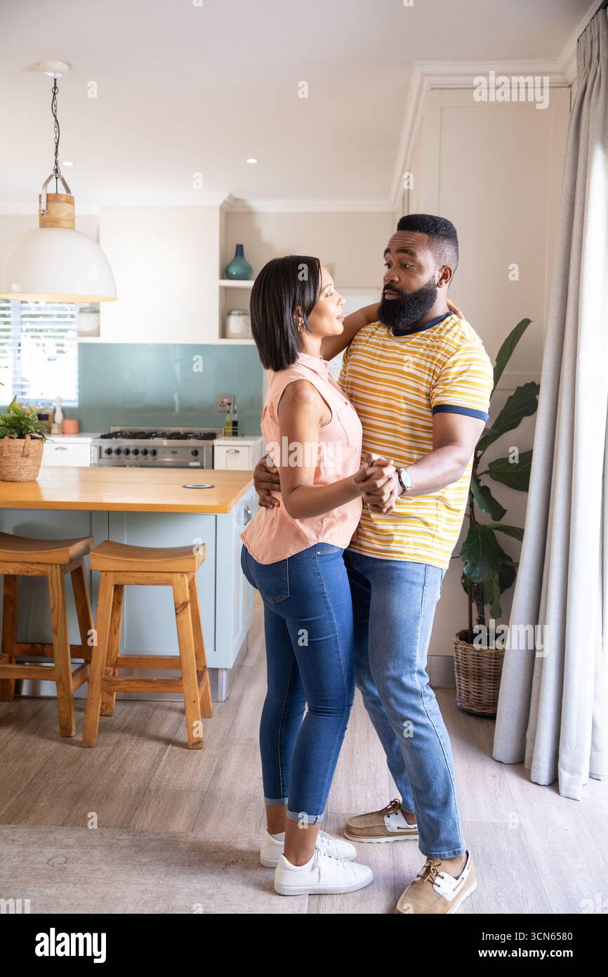 Diverse coppie che ballano e ondeggiano nella cucina moderna intorno all'isola sotto la luce a sospensione Foto Stock