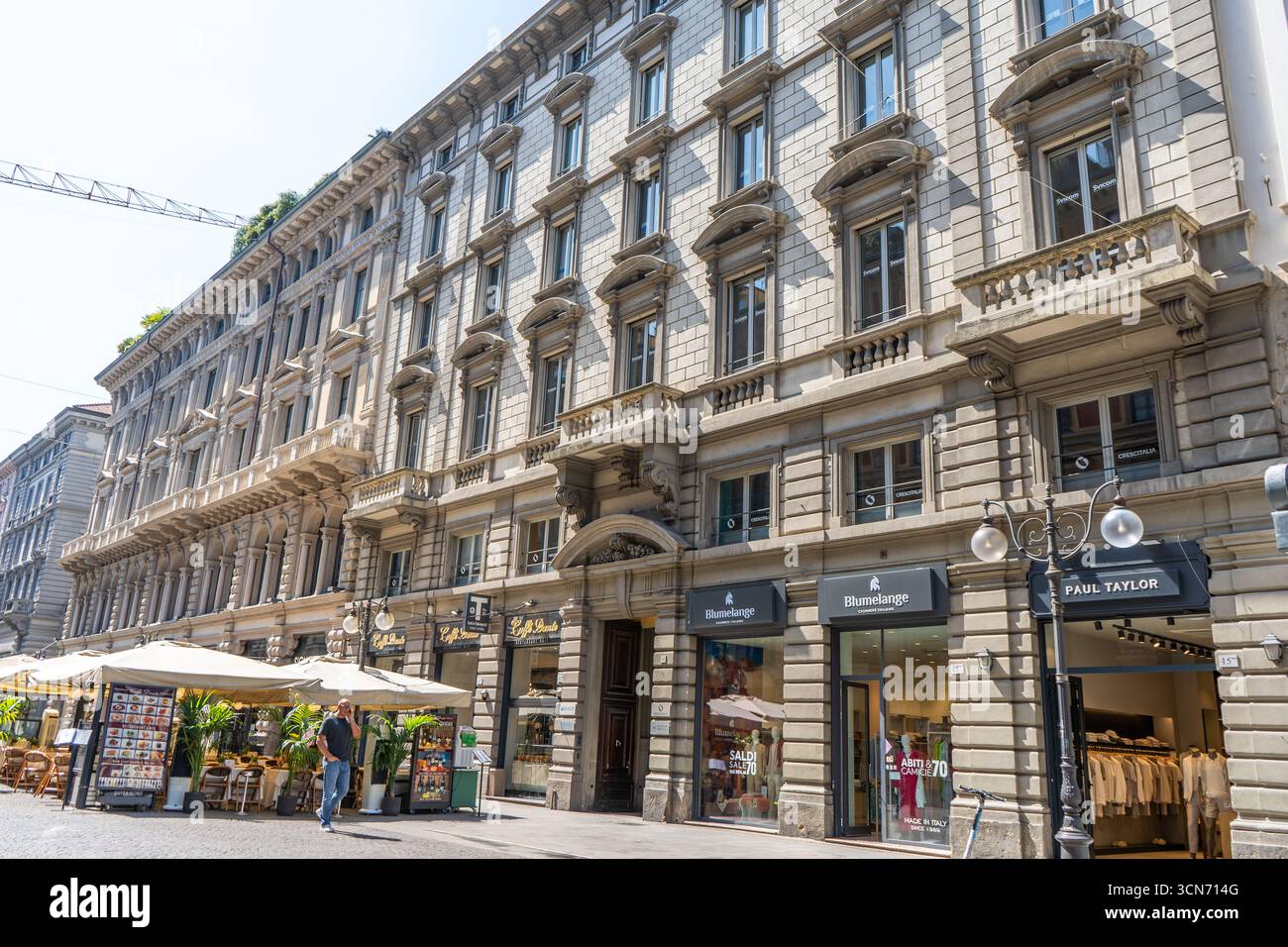 Facciata di una vecchia casa nel centro di Milano. Segno del marchio Blumelange, Paul Taylor Store. Ingresso ufficiale al negozio. La gente cammina l'estate. Italia, Milano - 17 luglio 2025 Foto Stock