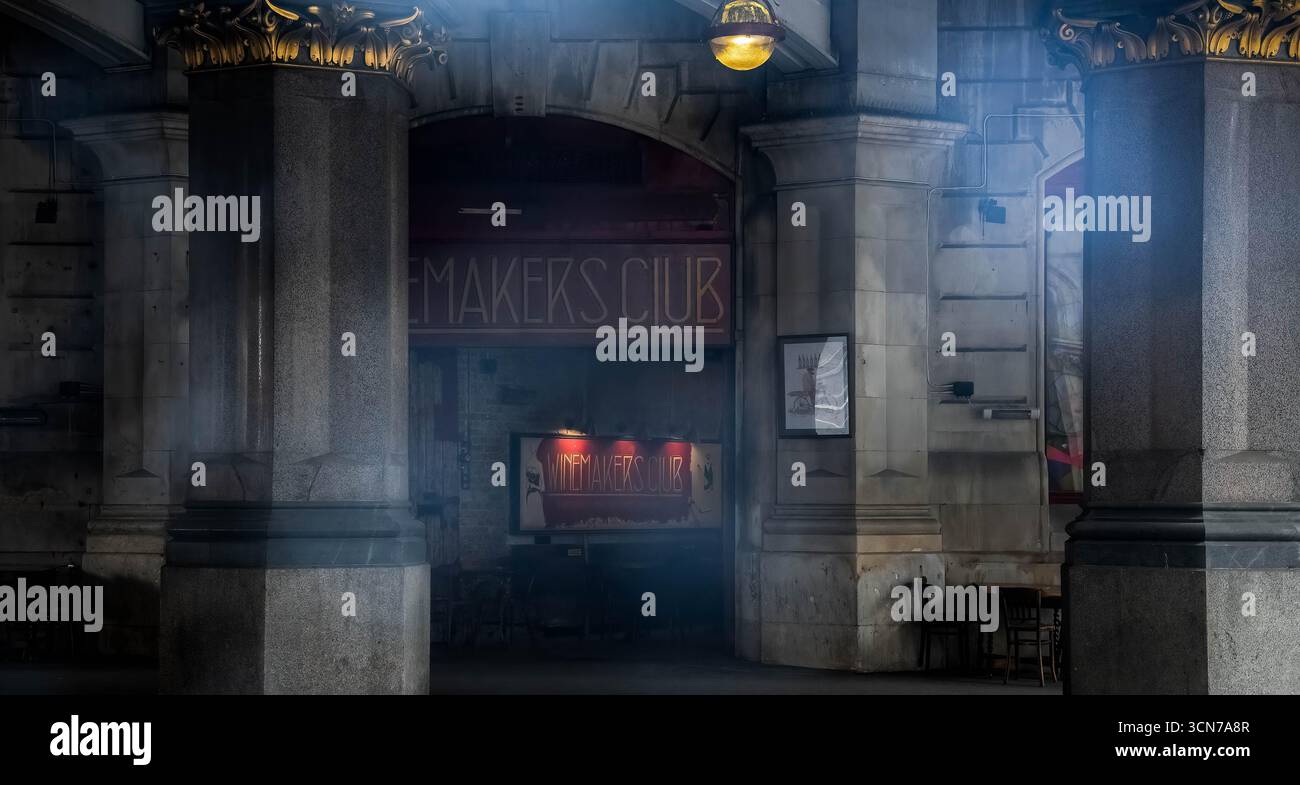 Vista suggestiva del Winemakers Club sotto il viadotto Holborn, con colonne in pietra, insegne vintage e illuminazione soffusa, City of London, Inghilterra Foto Stock