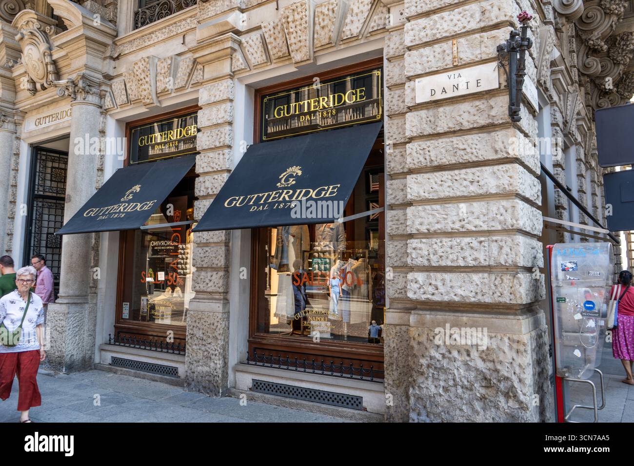 Italia, Milano - 17 luglio 2025: Vecchia casa via Dante facciata nel centro di Milano. Gutteridge Store logo marchio architettura ingresso ufficiale negozio. Foto Stock