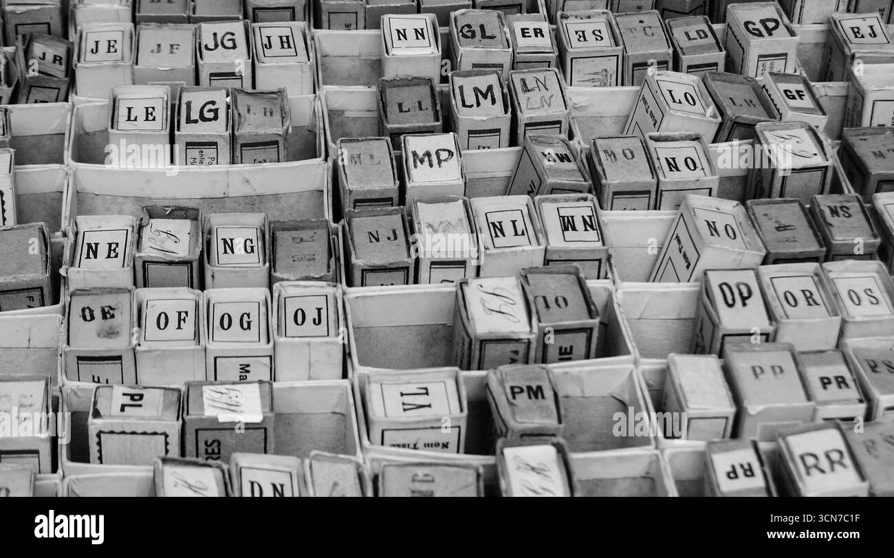 Pila di scatole di cartone con lettere alfabetiche e sillabe. Gioco d'epoca al mercato delle pulci di Parigi, Francia. Foto storica in bianco e nero. Foto Stock