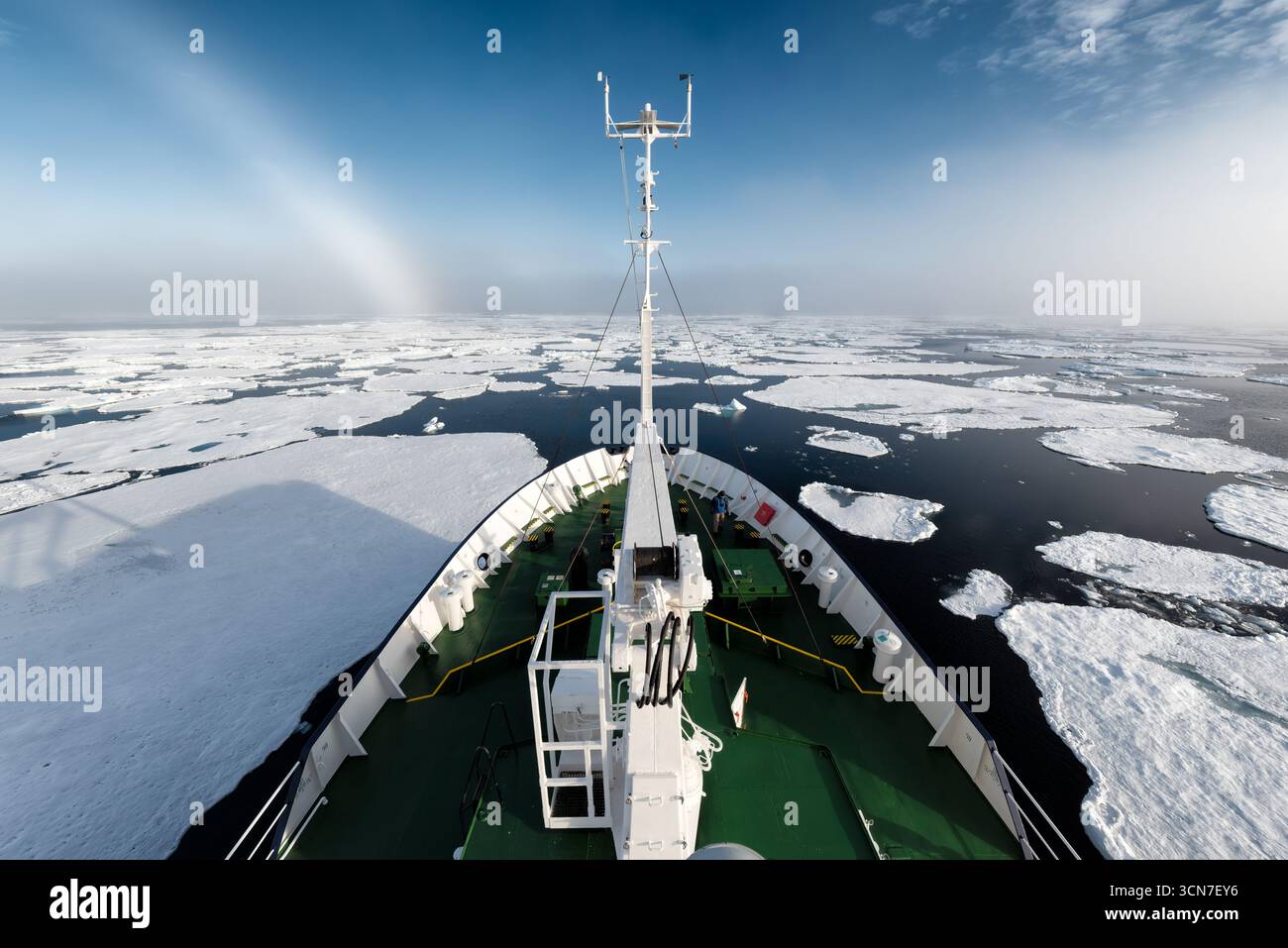 Ship Deck navigando sui banchi di ghiaccio artico SVALBARD Norvegia // SVALBARD, Norvegia — Una nave naviga attraverso banchi di ghiaccio sparsi nell'Oceano Artico al largo della costa delle Svalbard. L'immagine cattura la dura bellezza del paesaggio polare, con la prua della nave che taglia l'acqua scura in mezzo a una vasta distesa di ghiaccio. Le Svalbard, un arcipelago situato tra il Mare di Groenlandia e l'Oceano Artico, sono note per il loro ambiente estremo e la significativa copertura di ghiaccio. Questa regione è un'area cruciale per la ricerca scientifica relativa ai cambiamenti climatici e agli ecosistemi artici. Foto Stock