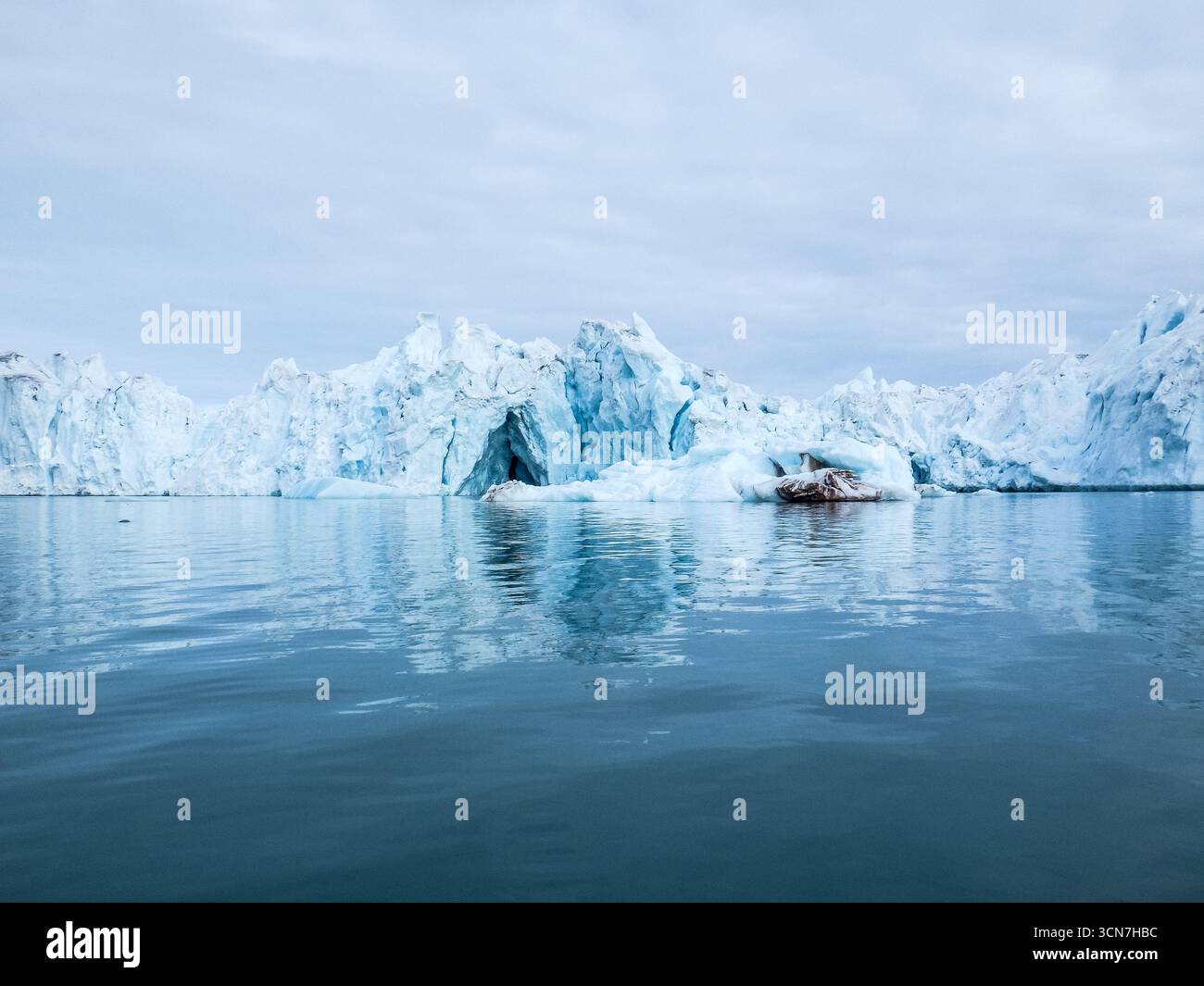 Ghiacciaio Klerckbukta Nordaustlandet Svalbard // NORDEAUSTLANDET, Svalbard e Jan Mayen - il ghiacciaio Klerckbukta è una caratteristica glaciale prominente su Nordaustlandet, la seconda isola più grande dell'arcipelago delle Svalbard. Questo ghiacciaio è caratterizzato dalle sue immense formazioni di ghiaccio, con crepacci visibili e una grotta di ghiaccio che si apre sul suo volto. Le acque circostanti riflettono il blu e il bianco del ghiaccio, una vista comune in questa regione artica. Nordaustlandet fa parte del vasto arcipelago delle Svalbard, un territorio norvegese situato nell'Oceano Artico, conosciuto per i suoi paesaggi suggestivi e unici Foto Stock