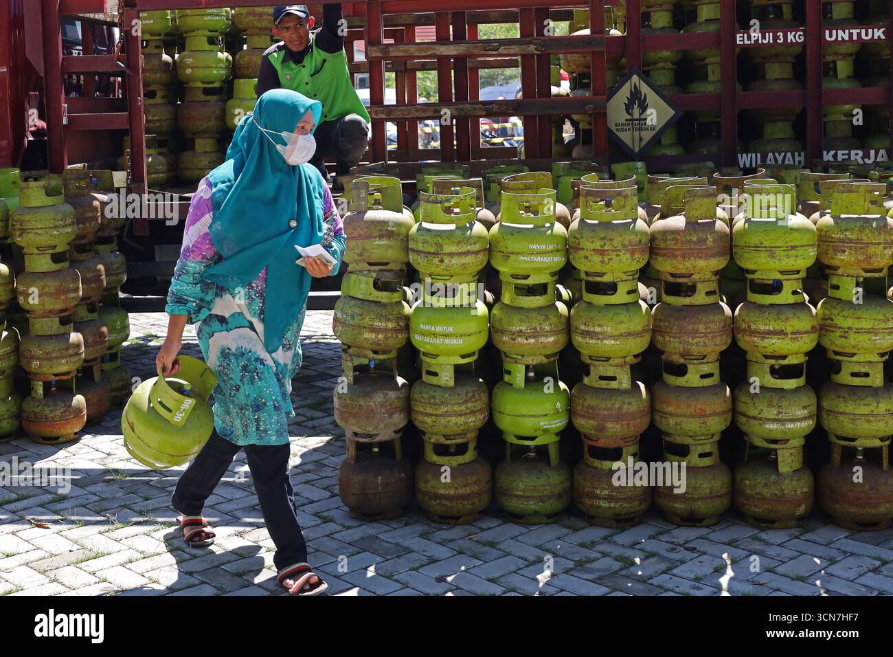 Banda Aceh, Aceh, Indonesia. 17 settembre 2025. I residenti trasportano bombole di gas sovvenzionate da 3 kg dopo aver superato la fila al mercato agricolo di banda Aceh City, provincia di Aceh, Indonesia. Pertamina Patra Niaga della regione di Sumbagut distribuì un ulteriore tubo GPL da 3 kg con un sussidio di 147.280 tubi, o 105%, ad Aceh per rafforzare l'approvvigionamento e prevenire interferenze con la distribuzione. Nel 2025 il governo indonesiano ha stanziato circa 87,6000 miliardi di dollari per sovvenzioni al GPL di 3 kg, con un bilancio totale di sovvenzioni all'energia e compensazioni di 394000 miliardi di dollari. (Immagine di credito: © Khairu Syukrillah/ZUMA Pr Foto Stock