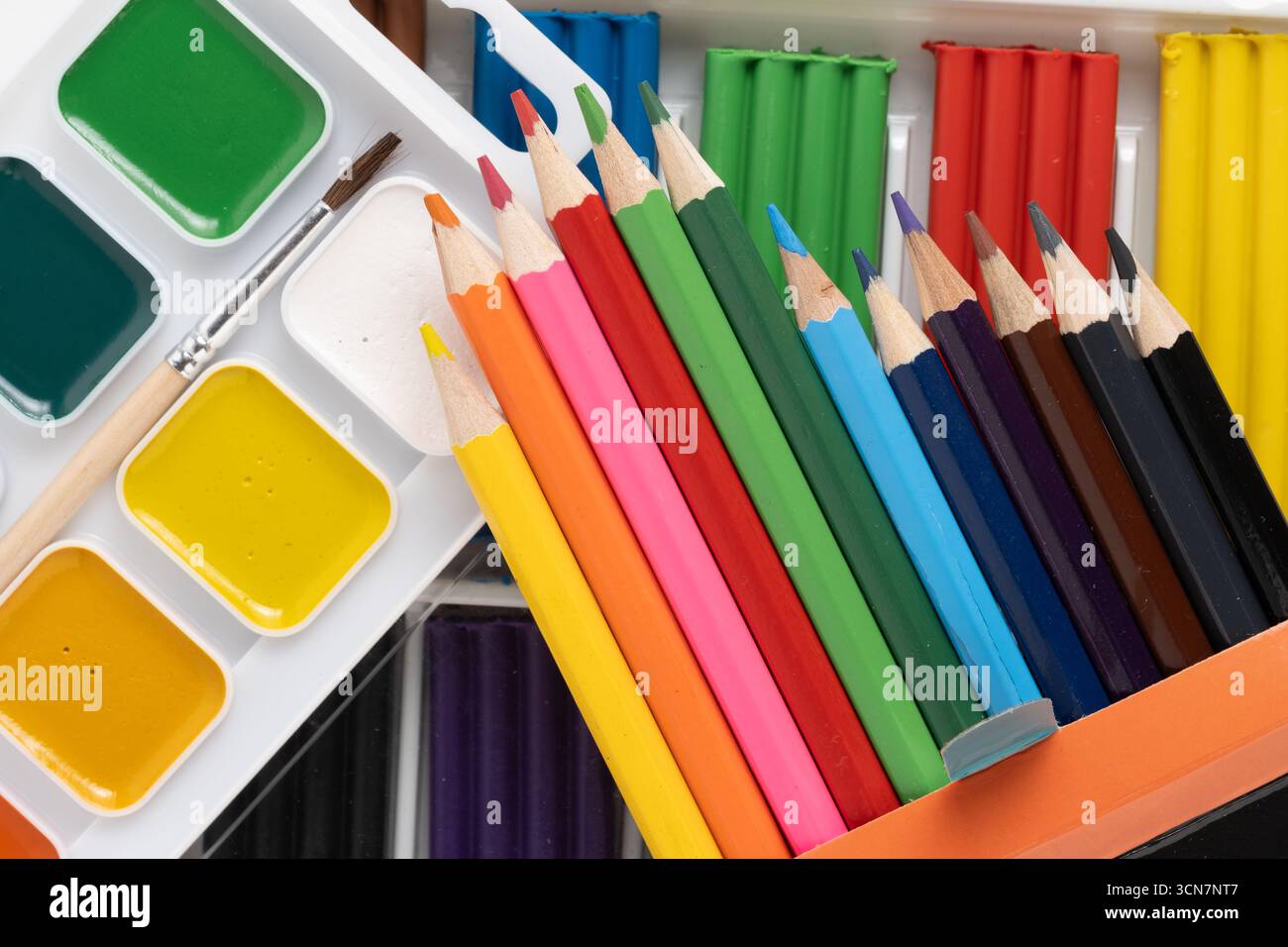 Matite colorate, plasticine e vernici ad acquerello in scatola bianca Foto Stock