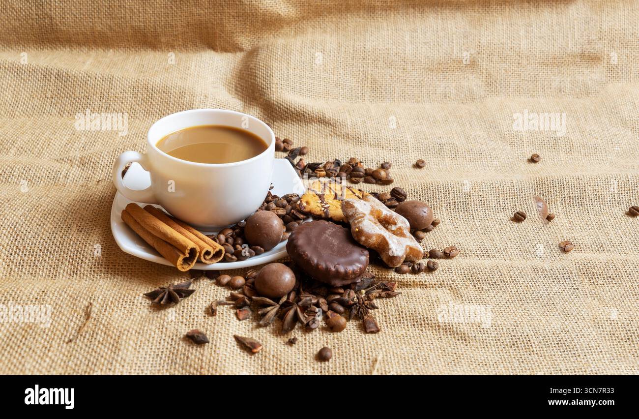 Una tazza bianca con un piattino e caffè e chicchi di caffè su fondo marrone Foto Stock