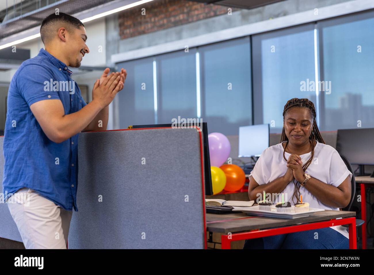 Diversi colleghi applaudono donne afroamericane in ufficio con cupcake e spazio per le copie Foto Stock