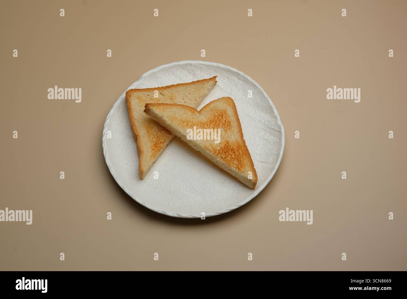 Delizioso pane tostato dorato servito splendidamente su un piatto bianco per il tuo divertimento Foto Stock