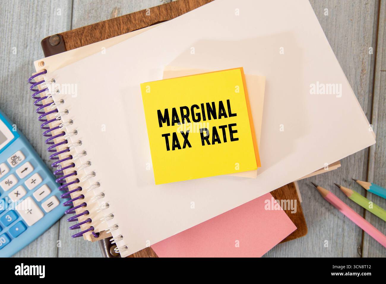Su un blocco note rosso un foglio di carta con testo aliquota fiscale marginale Foto Stock