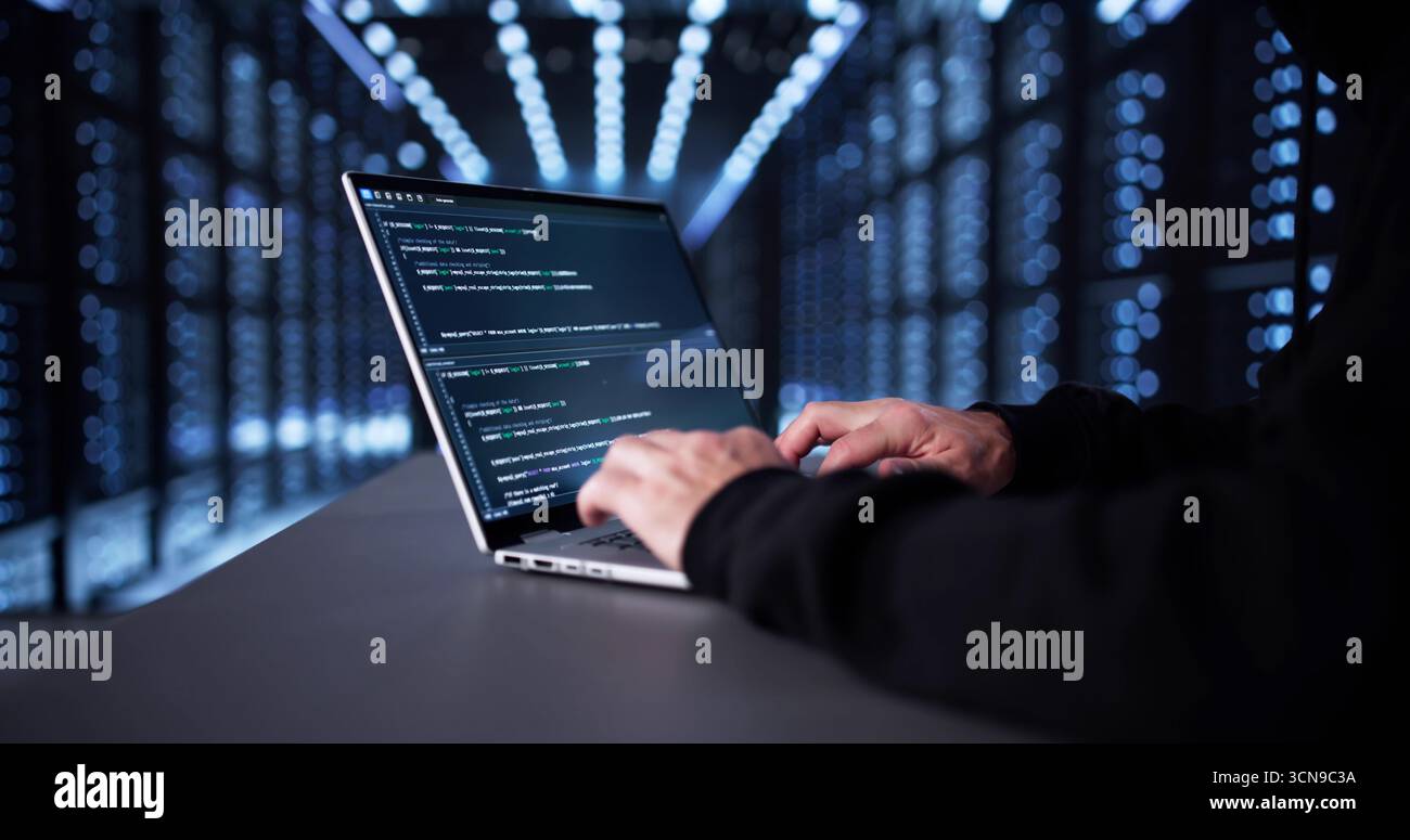 Man in Dark Hoodie Hacks nel server online per Cyberattack. Foto Stock