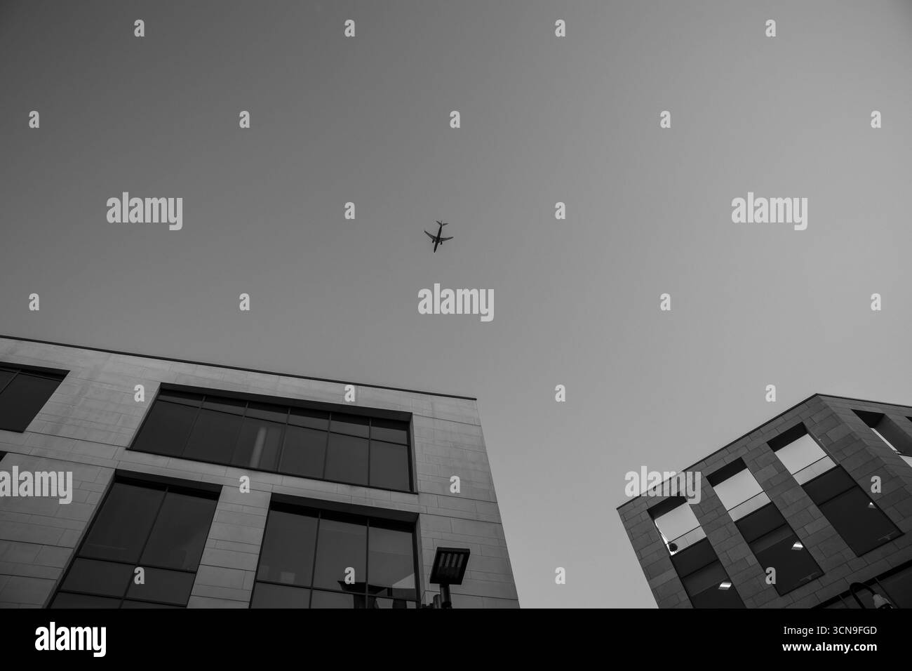 Aereo che vola sopra moderni edifici di uffici in bianco e nero Foto Stock