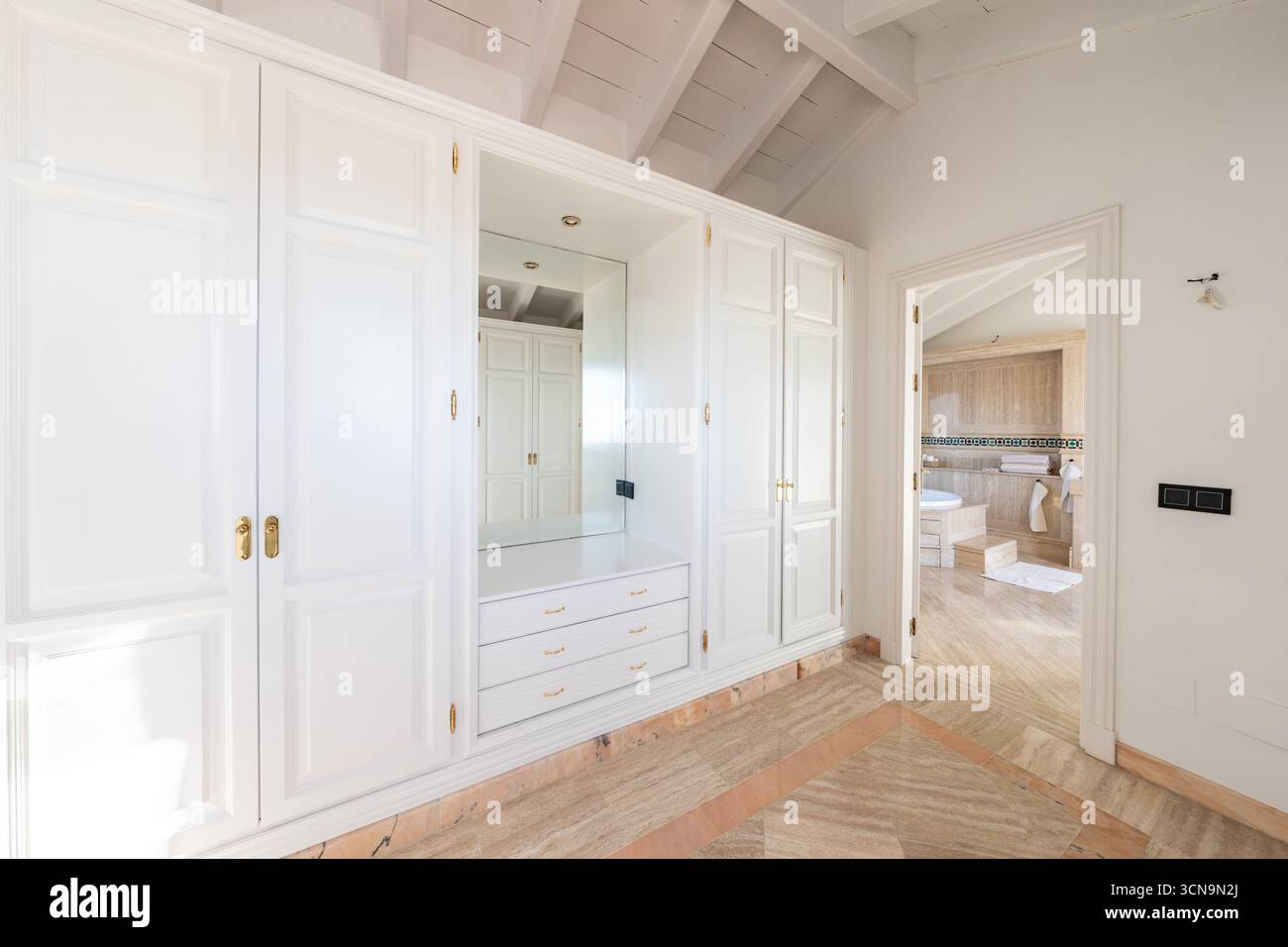 un'immagine di un grande armadio bianco accanto al bagno privato nella camera da letto principale Foto Stock
